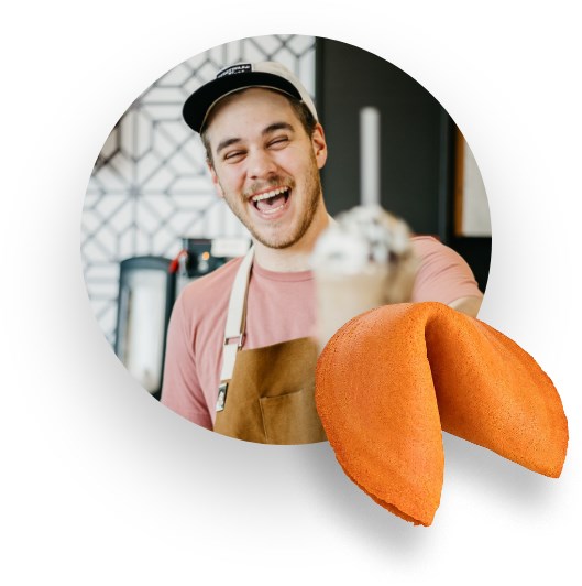 Oranger Glückskeks, im Hintergrund ein lachender junger Mann