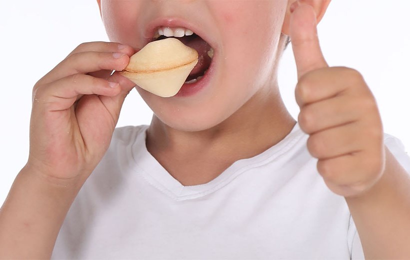Child eats fortune cookie and holds thumb up