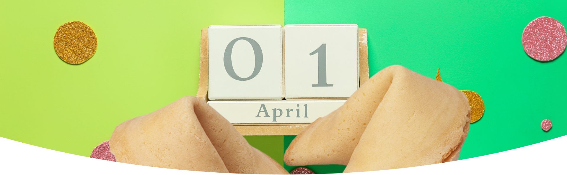 Zwei Glückskekse mit einem Kalender 01 April dahinter und einem Hintergrund in verschiedenen Grüntönen mit Glitzerkonfetti zum 1. April